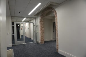 Interior hallway with a brick archway and glass doors in a modern building. (informative)
