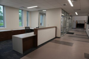 Modern office reception with a wood-and-marble front desk and mesh chairs under large windows