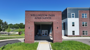 Front view of Willington Park Apartments with a brick entryway under a clear blue sky.