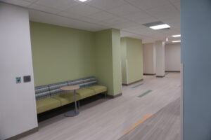 Colorful waiting area with lime green walls, cushioned bench seating, and a small round table in a modern interior hallway.