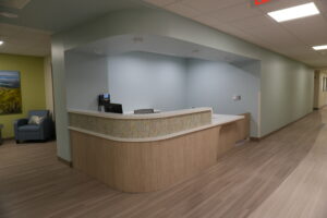Curved reception desk in a light blue-walled lobby with a Mosaic-front panel and nearby seating area visible to the left.