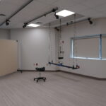 Rehabilitation studio with ceiling-mounted suspension track and harness system in an empty room.