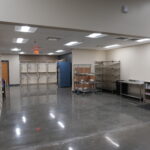 Industrial storage room with metal shelving, carts, and cabinets; open floor space in the center.