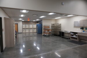 Industrial storage room with metal shelving, carts, and cabinets; open floor space in the center.