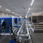 Automated assembly line with blue robotic modules and conveyor belts in a spacious, well-lit facility.