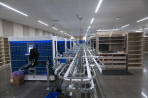 Automated assembly line with blue robotic modules and conveyor belts in a spacious, well-lit facility.