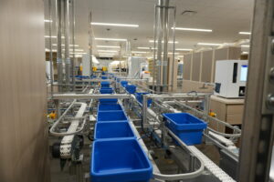 Industrial warehouse with an automated conveyor system and blue plastic bins for sorting goods.