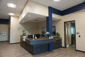 Reception desk in a modern pharmacy lobby with a dark wood counter, blue column, and a Norton Pharmacy sign on a beige wall.