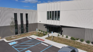 Exterior view of a modern office building with blue-accessible parking spaces and a wheelchair-accessible path to the entrance.